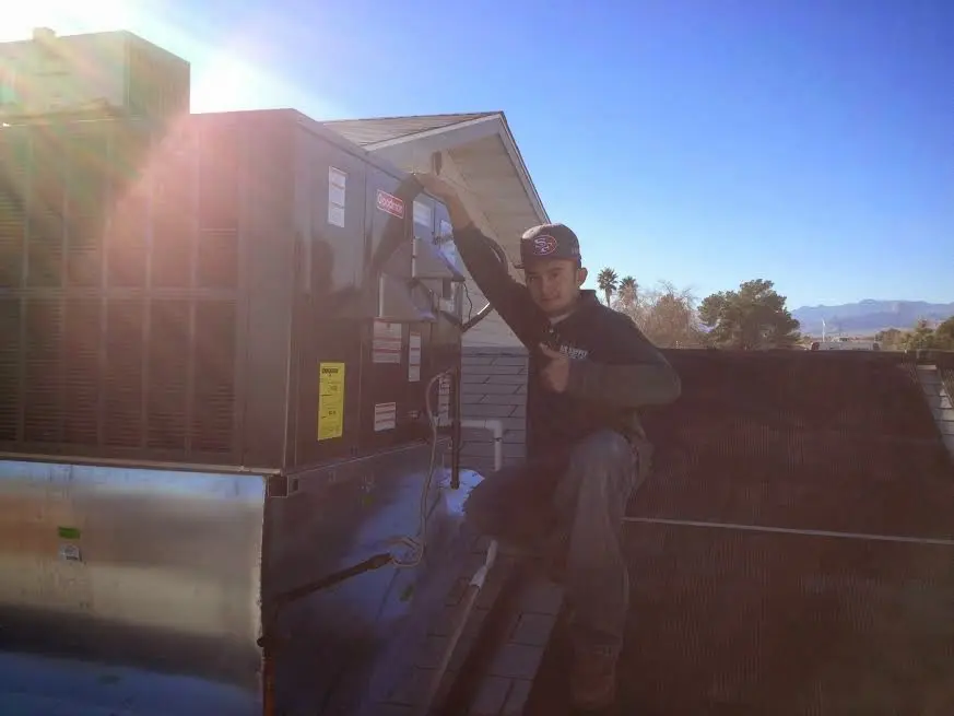 HVAC technician performing AC Tune-Up on a rooftop unit in Burleson
