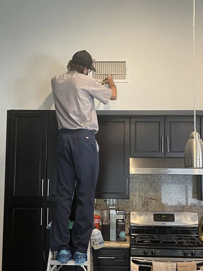 Technician inspecting an air vent during HVAC service in Burleson